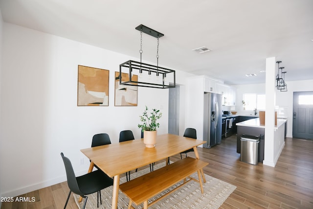 dining area with baseboards, visible vents, and wood finished floors