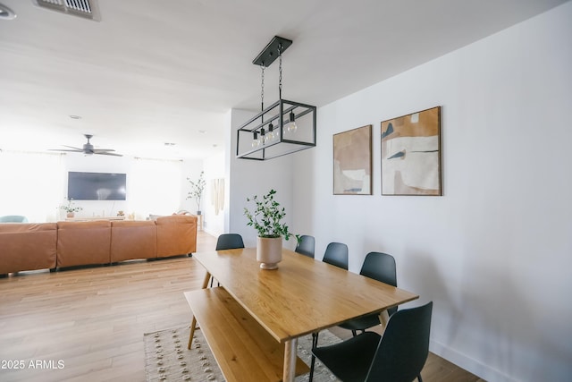 dining area with light wood-type flooring, a ceiling fan, baseboards, and visible vents