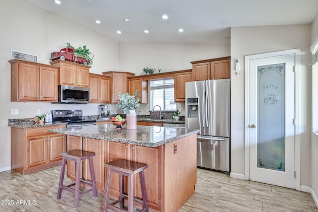7125 W Canterbury Dr, Peoria, AZ 85345 - kitchen featuring stainless steel appliances, high vaulted ceiling, a center island, light wood-style floors, and dark stone countertops
