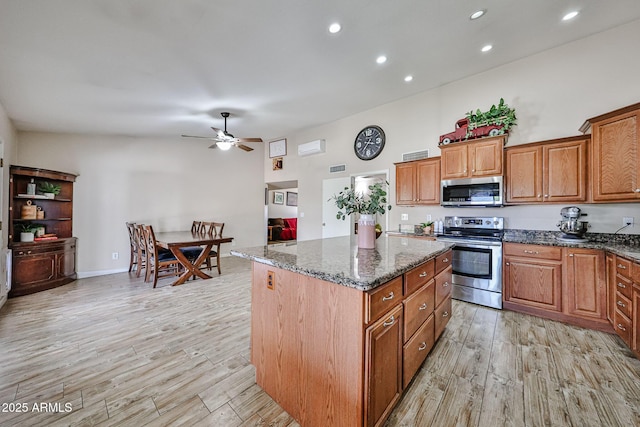 7125 W Canterbury Dr, Peoria, AZ 85345 - kitchen with appliances with stainless steel finishes, light wood-type flooring, ceiling fan, brown cabinets, and a center island