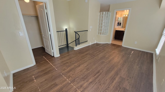 5628 S 21st Pl, Phoenix, AZ 85040 - unfurnished bedroom featuring dark wood-type flooring, baseboards, a closet, and a walk in closet