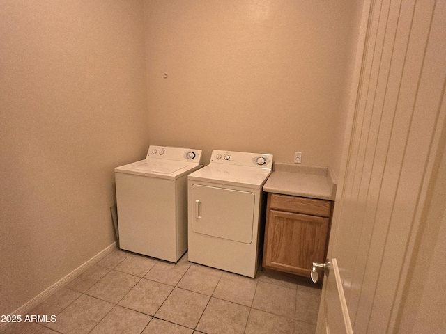 washroom featuring separate washer and dryer, light tile patterned floors, and cabinets