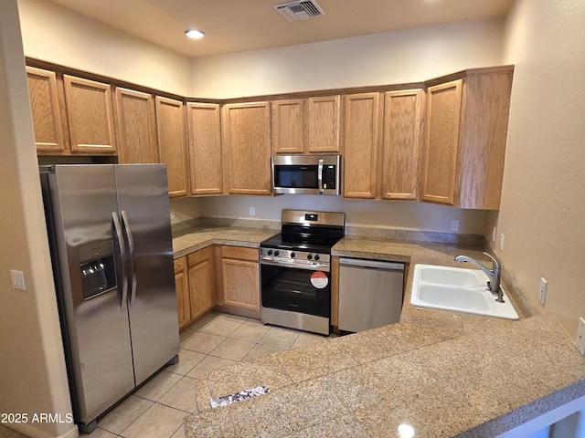 kitchen with light tile patterned flooring, appliances with stainless steel finishes, kitchen peninsula, and sink