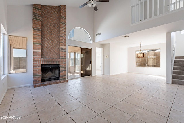 unfurnished living room featuring visible vents, ceiling fan, stairway, a fireplace, and light tile patterned flooring