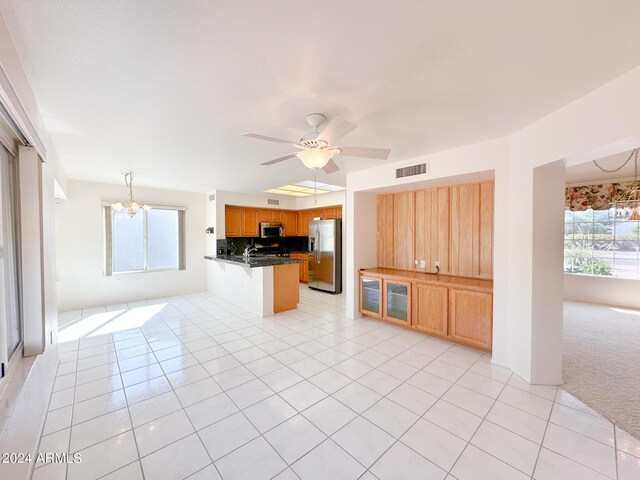 kitchen featuring tasteful backsplash, stainless steel appliances, kitchen peninsula, light colored carpet, and ceiling fan with notable chandelier