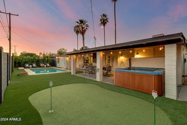 back house at dusk with a patio area and a swimming pool with hot tub