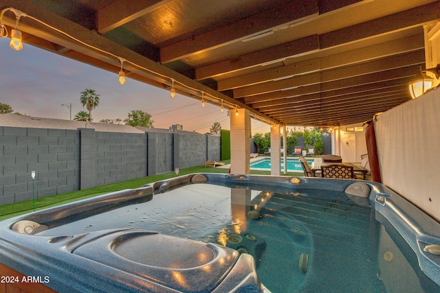 pool at dusk with a hot tub