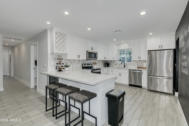 kitchen featuring backsplash, sink, appliances with stainless steel finishes, kitchen peninsula, and white cabinets