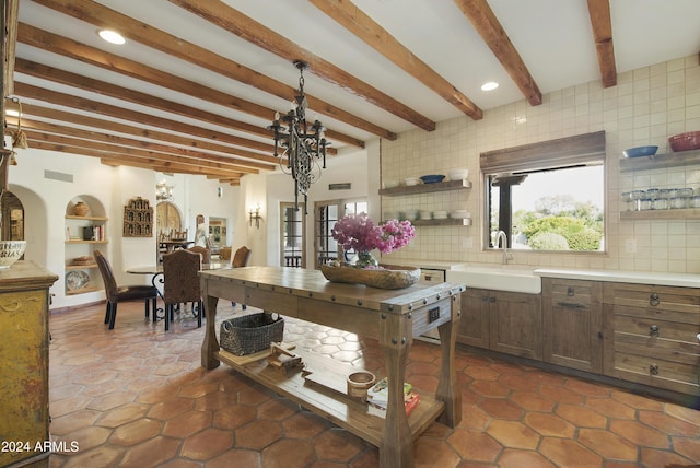 kitchen featuring beam ceiling, sink, decorative backsplash, and a chandelier