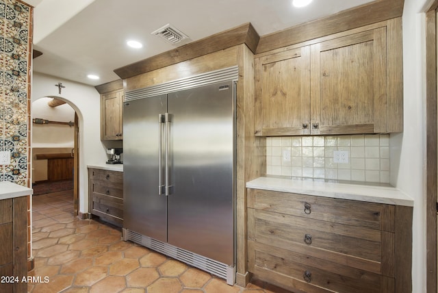 kitchen with light tile patterned floors, decorative backsplash, and stainless steel built in fridge