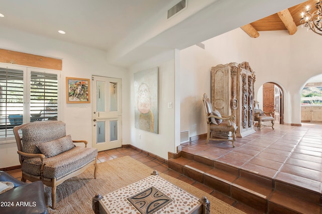 living room featuring beam ceiling, a chandelier, tile patterned flooring, and wooden ceiling