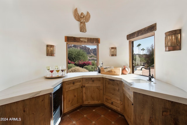 kitchen with wine cooler, kitchen peninsula, sink, and dark tile patterned floors