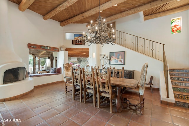 dining space with tile patterned flooring, a fireplace, beamed ceiling, wooden ceiling, and a chandelier