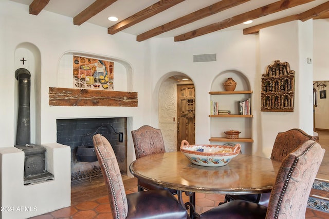 dining room with tile patterned flooring, beamed ceiling, and a wood stove