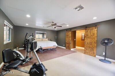 bedroom featuring a barn door, ceiling fan, and multiple windows