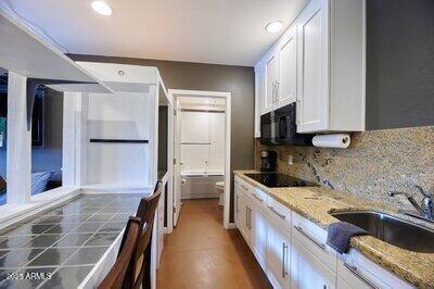 kitchen featuring black appliances, light stone counters, white cabinetry, and sink