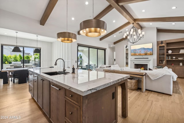 kitchen featuring sink, a center island with sink, vaulted ceiling with beams, and pendant lighting