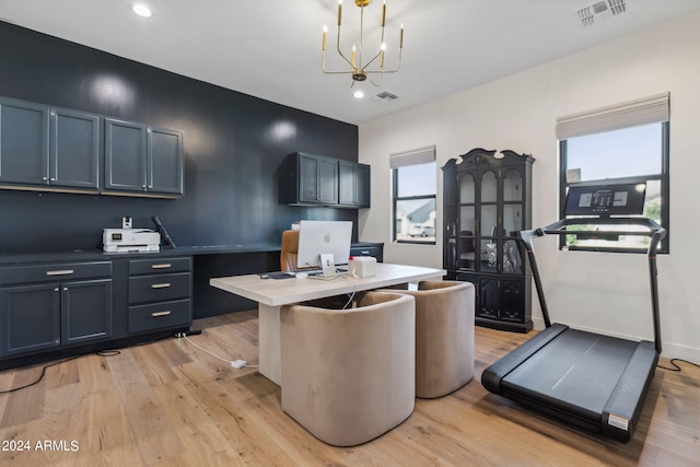 kitchen featuring light hardwood / wood-style floors, a notable chandelier, decorative light fixtures, and a kitchen island with sink