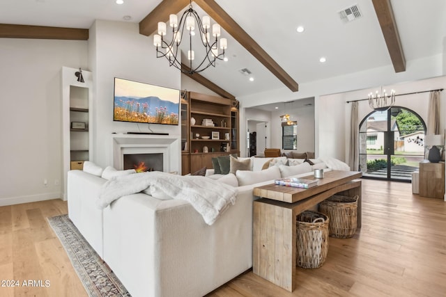 living room with light hardwood / wood-style flooring, built in features, vaulted ceiling with beams, and a chandelier