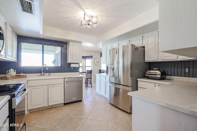 kitchen featuring sink, light tile patterned floors, white cabinetry, stainless steel appliances, and decorative backsplash