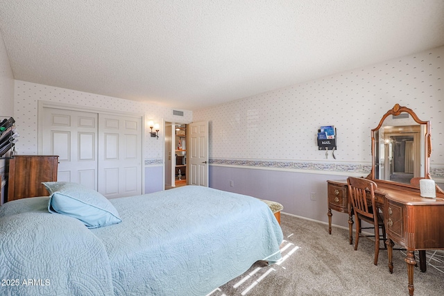 carpeted bedroom with a closet and a textured ceiling