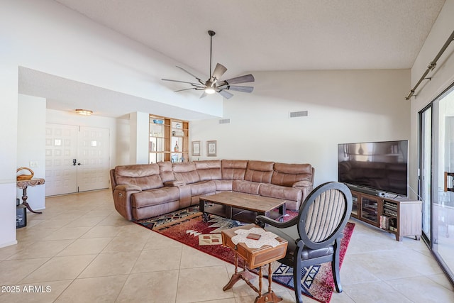 tiled living room featuring ceiling fan, high vaulted ceiling, and a textured ceiling