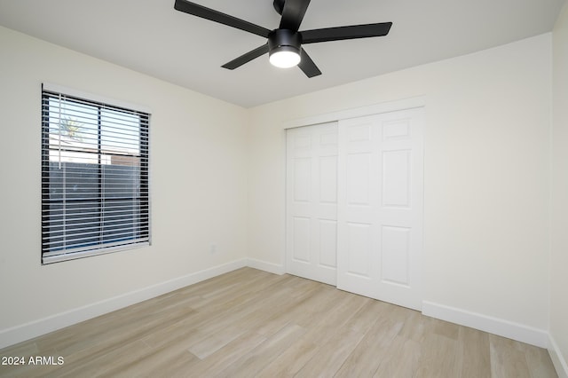 unfurnished bedroom featuring ceiling fan, a closet, and light wood-type flooring