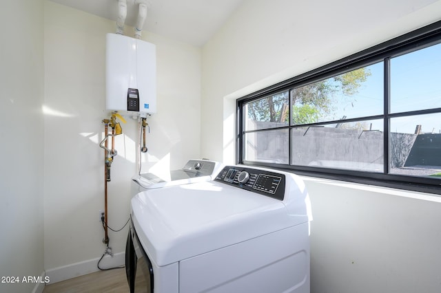 laundry room with light hardwood / wood-style floors, separate washer and dryer, and water heater