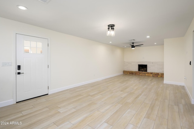 unfurnished living room with ceiling fan, light hardwood / wood-style floors, and brick wall