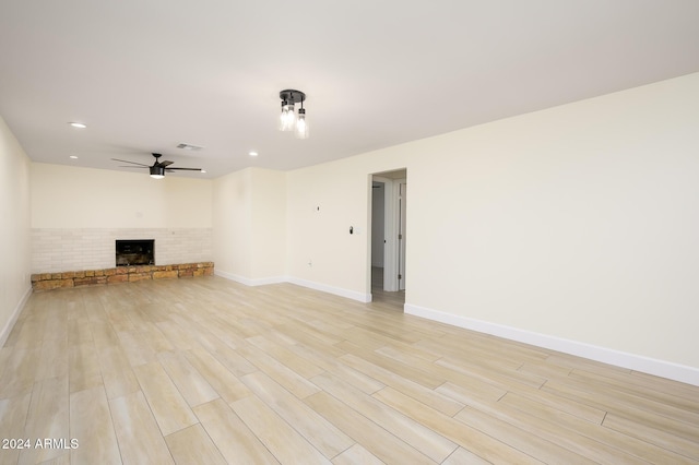 unfurnished living room with light hardwood / wood-style floors, a brick fireplace, and ceiling fan