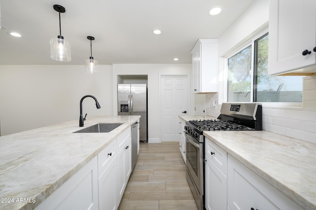 kitchen featuring decorative backsplash, light stone counters, stainless steel appliances, sink, and white cabinetry