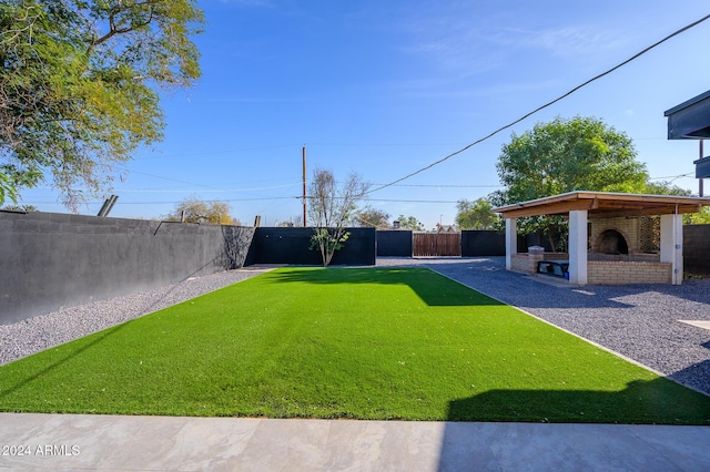 view of yard with a gazebo, an outdoor brick fireplace, and a patio area