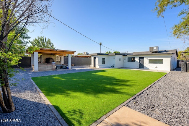 rear view of property featuring a brick fireplace, cooling unit, a patio area, and a lawn