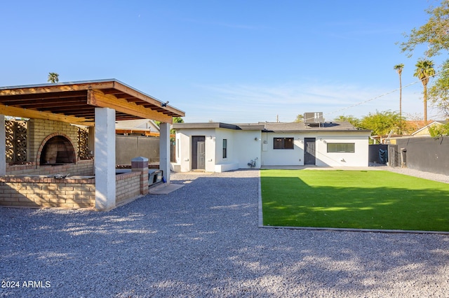 rear view of property featuring a lawn, area for grilling, and exterior fireplace