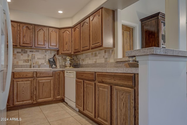 kitchen with light tile patterned floors, white appliances, backsplash, and sink