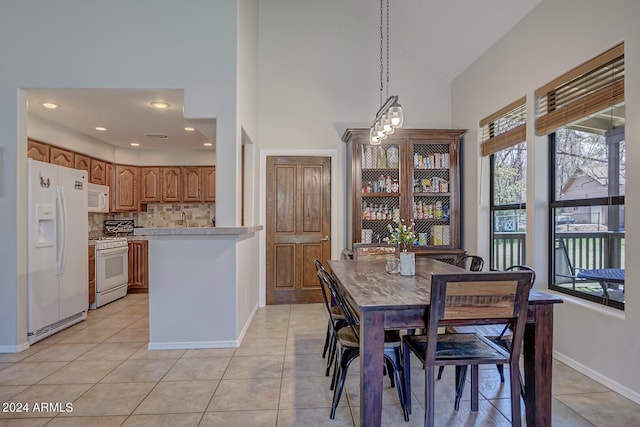 dining space featuring light tile patterned flooring and high vaulted ceiling