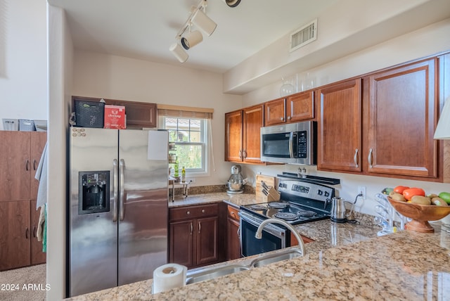 kitchen with light stone countertops, sink, stainless steel appliances, and track lighting