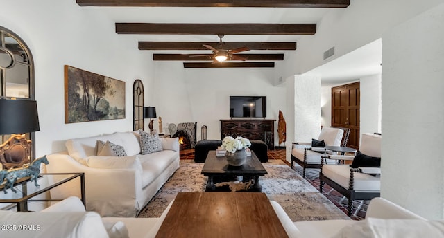 living room with ceiling fan, a large fireplace, and beamed ceiling