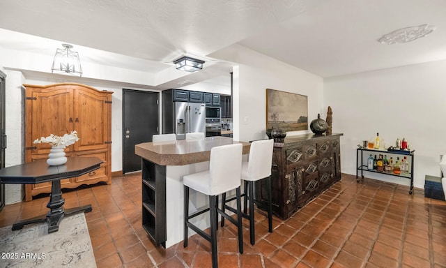 kitchen featuring kitchen peninsula, black microwave, a kitchen breakfast bar, and stainless steel refrigerator with ice dispenser