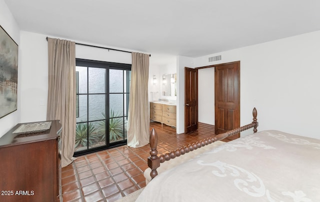 bedroom with ensuite bathroom and tile patterned floors