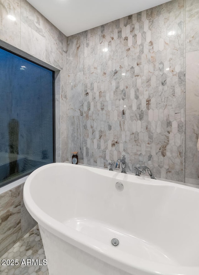 bathroom featuring tile patterned flooring, tile walls, and a tub