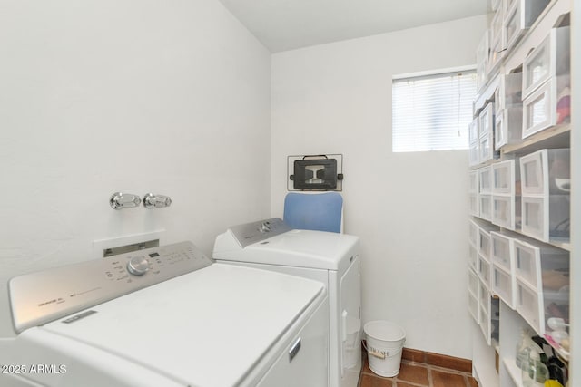 laundry area featuring washing machine and clothes dryer and dark tile patterned flooring