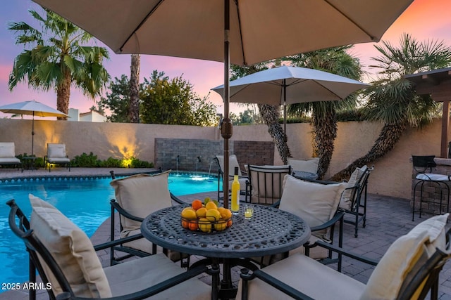 pool at dusk featuring pool water feature and a patio area