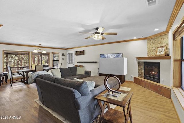 living room with hardwood / wood-style floors, ornamental molding, a tile fireplace, and ceiling fan