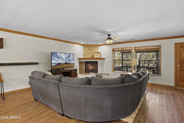 living room featuring crown molding, wood-type flooring, ceiling fan, and a fireplace