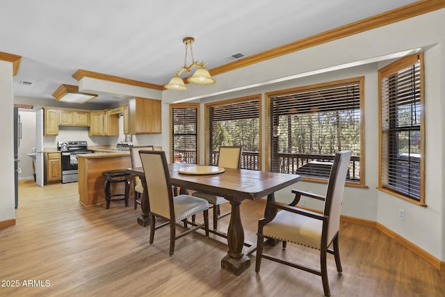 dining area with ornamental molding, a chandelier, and light wood-type flooring