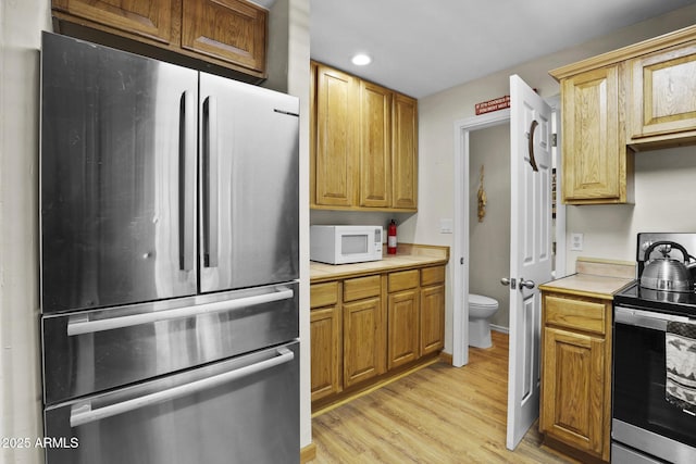 kitchen with appliances with stainless steel finishes and light hardwood / wood-style flooring