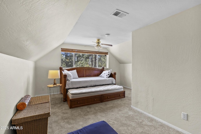 bedroom with light colored carpet, ceiling fan, vaulted ceiling, and a textured ceiling