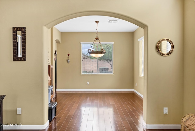 interior space with arched walkways, visible vents, dark wood finished floors, and baseboards