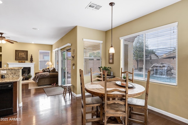 dining space with dark wood-type flooring, a ceiling fan, visible vents, and baseboards